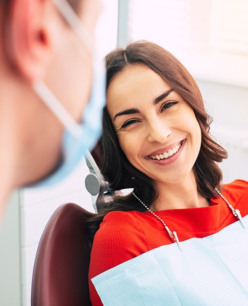 Woman in dental chair laughing with dentist