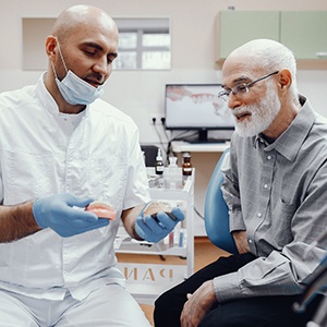 An older, balding man talking with his dentist about dentures