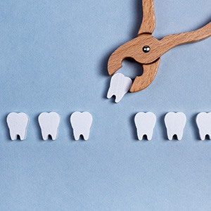 Bird’s eye view of a row of toy wooden teeth with one being pulled away by wooden forceps