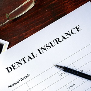 Top left corner of a blank dental insurance form next to dollar bills, glasses, and a pen