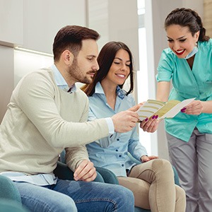 Medical professional discussing pamphlet of information with a man and woman in the waiting room