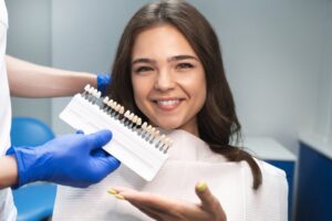 patient smiling with a color guide next to her for veneers